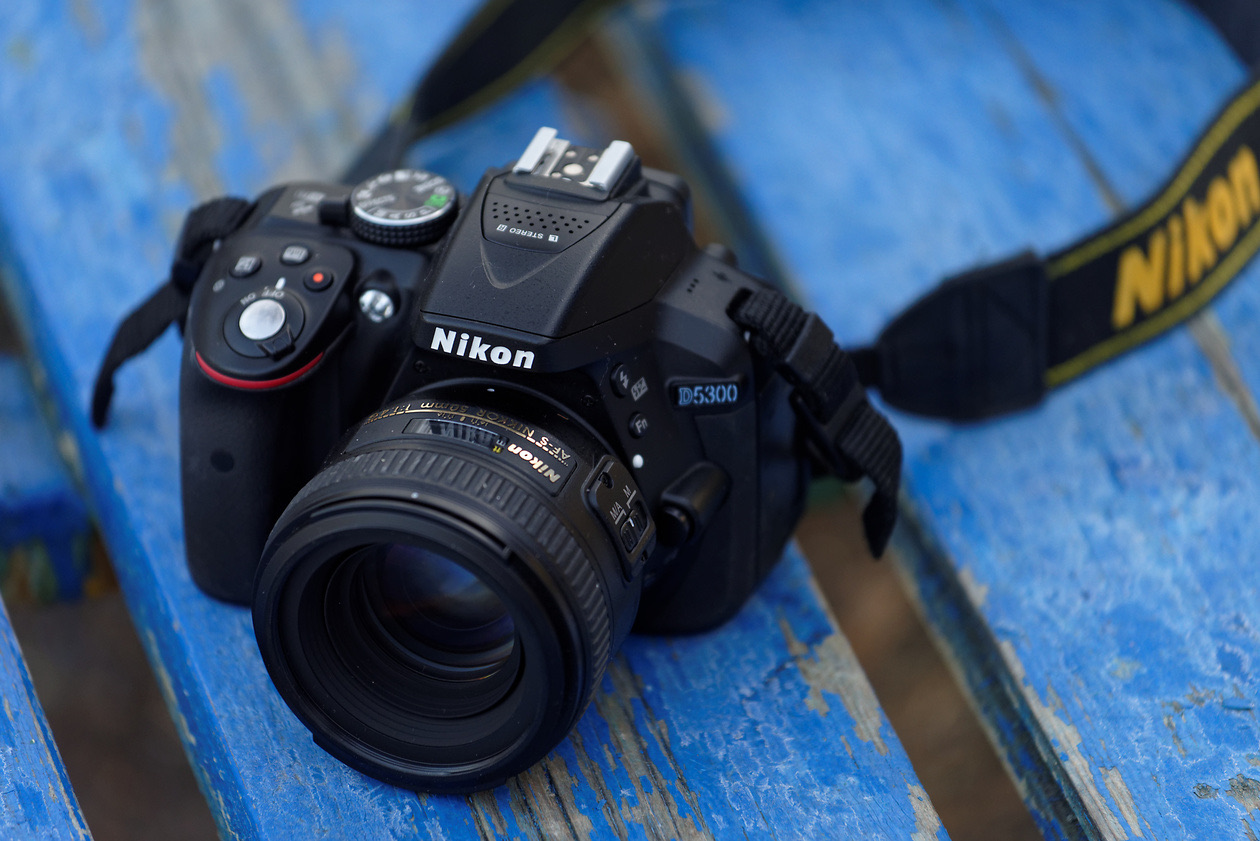 Entry-level Nikon DSLR with a prime lens lying on a weathered blue bench